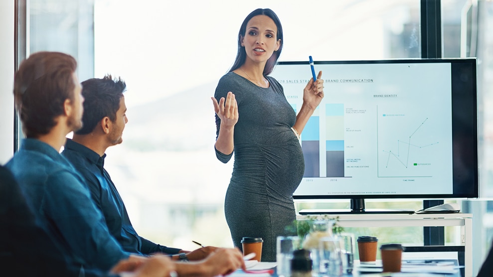 pregnant woman presenting a bar chart at work